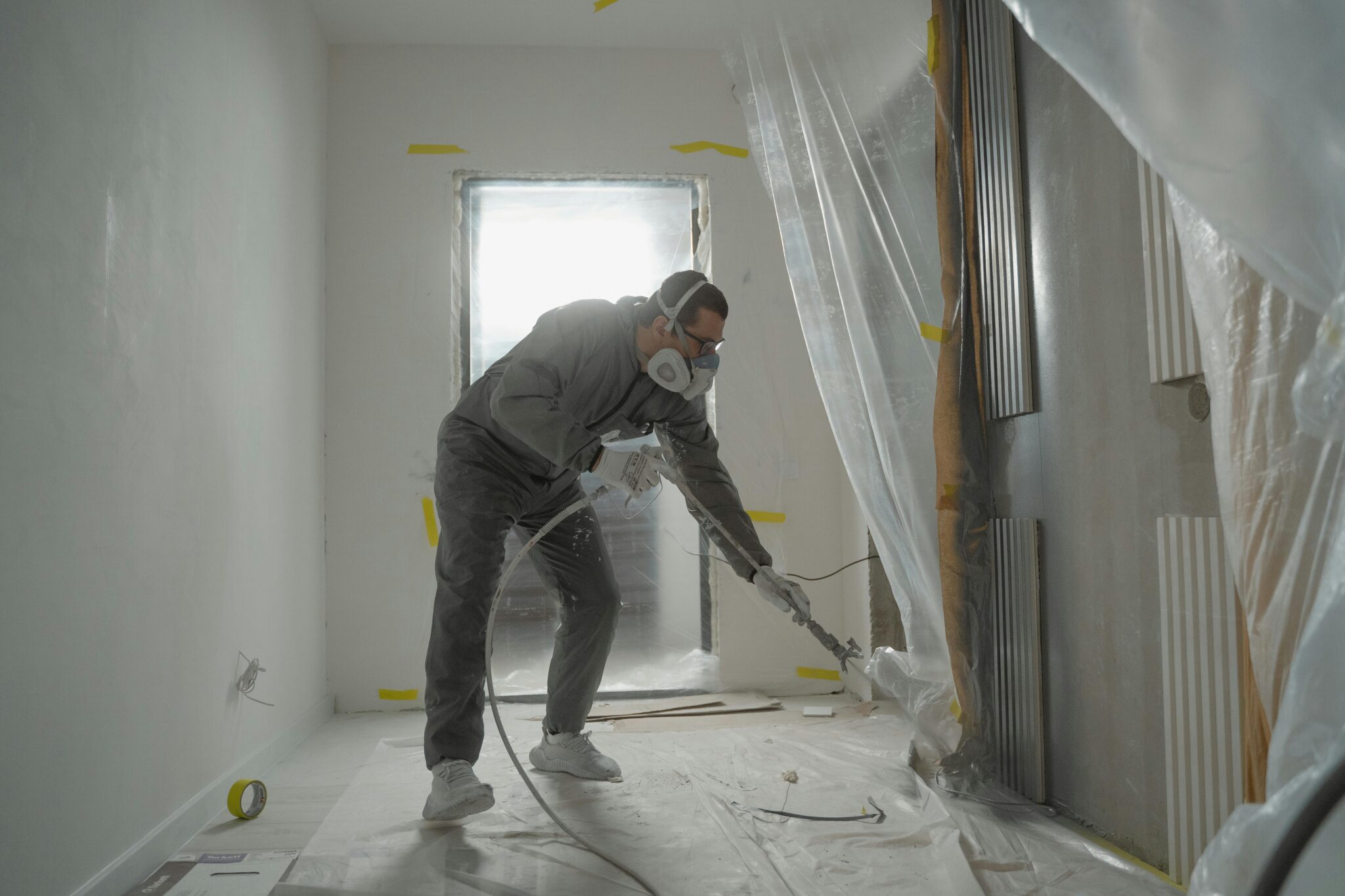 A worker in protective gear removing mold
