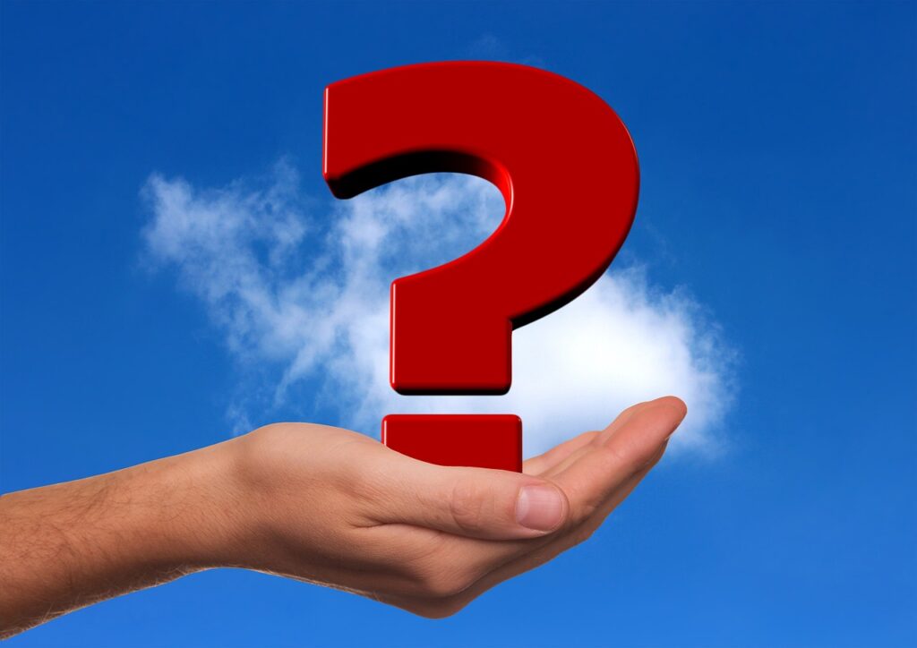 A hand hold a large red question mark, against a blue sky