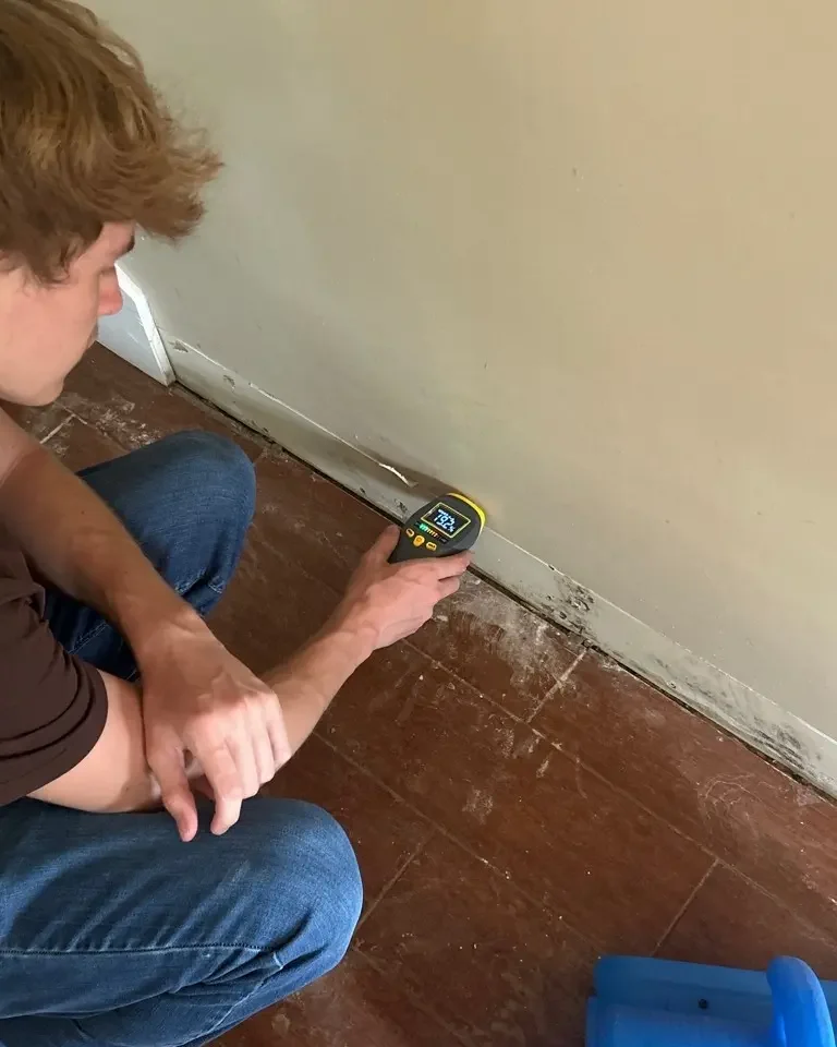 echnician using a professional moisture meter to locate hidden water damage in a Nashville home.